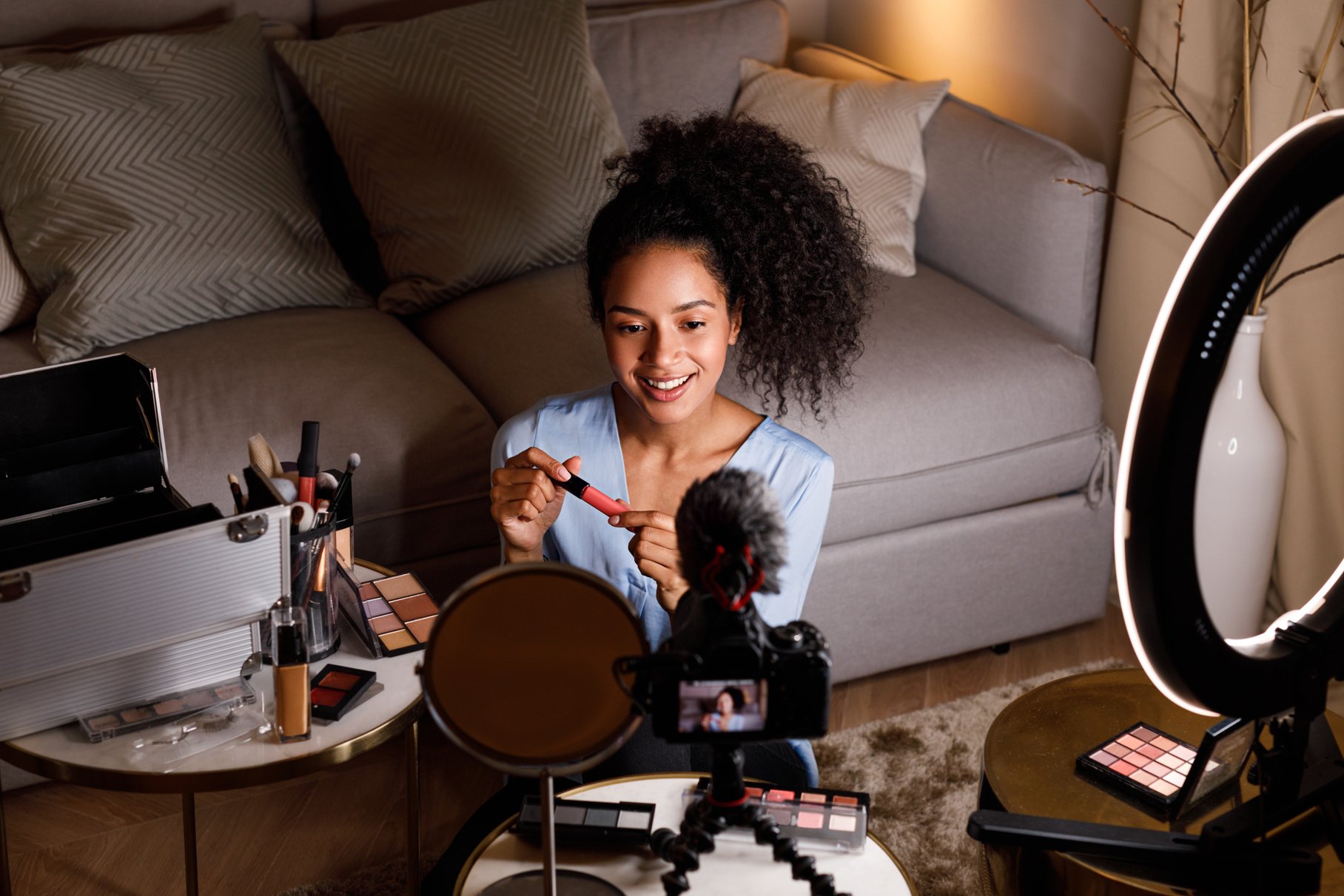 Young influencer making review for lipstick in living room