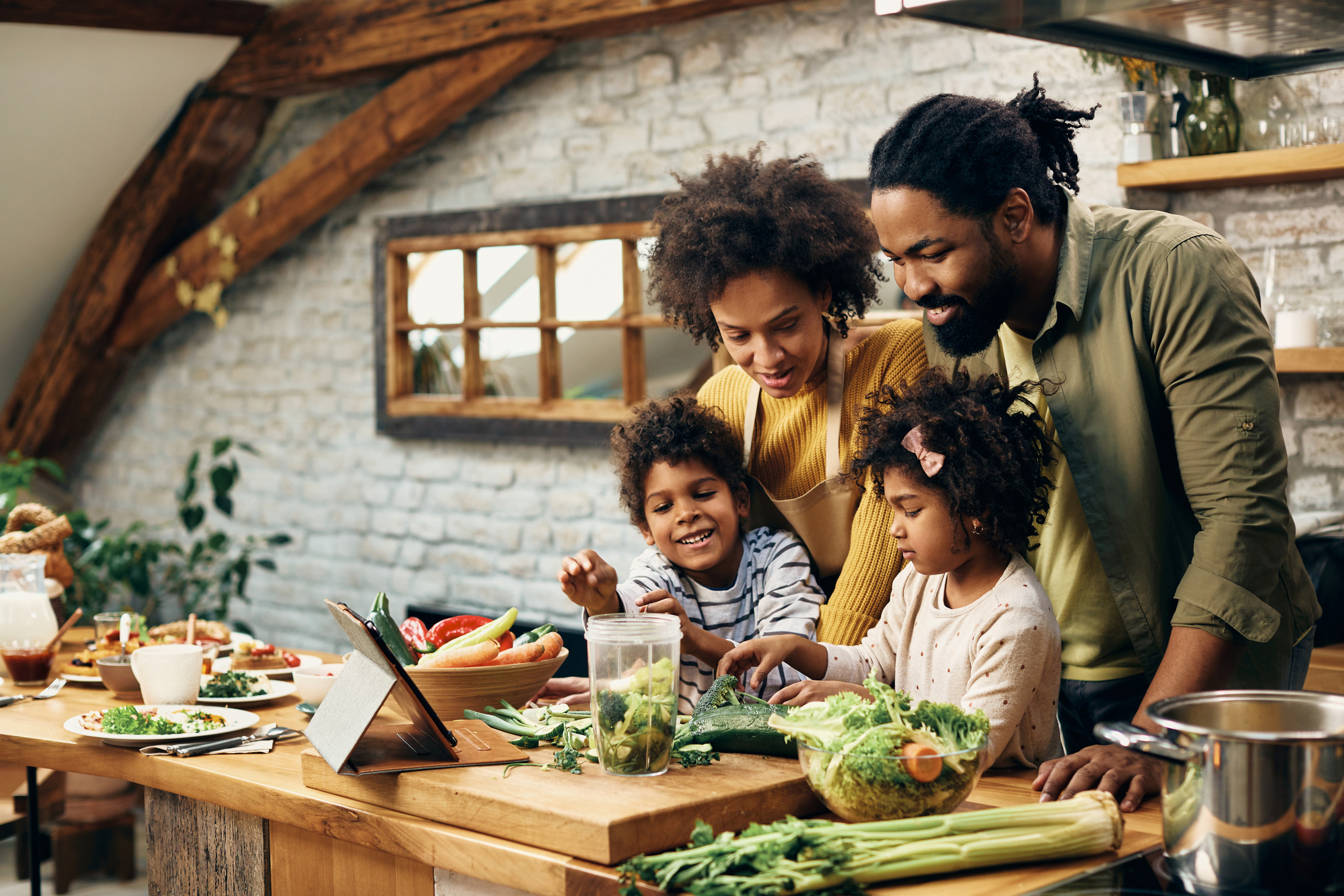 Happy black family preparing healthy food in the kitchen.